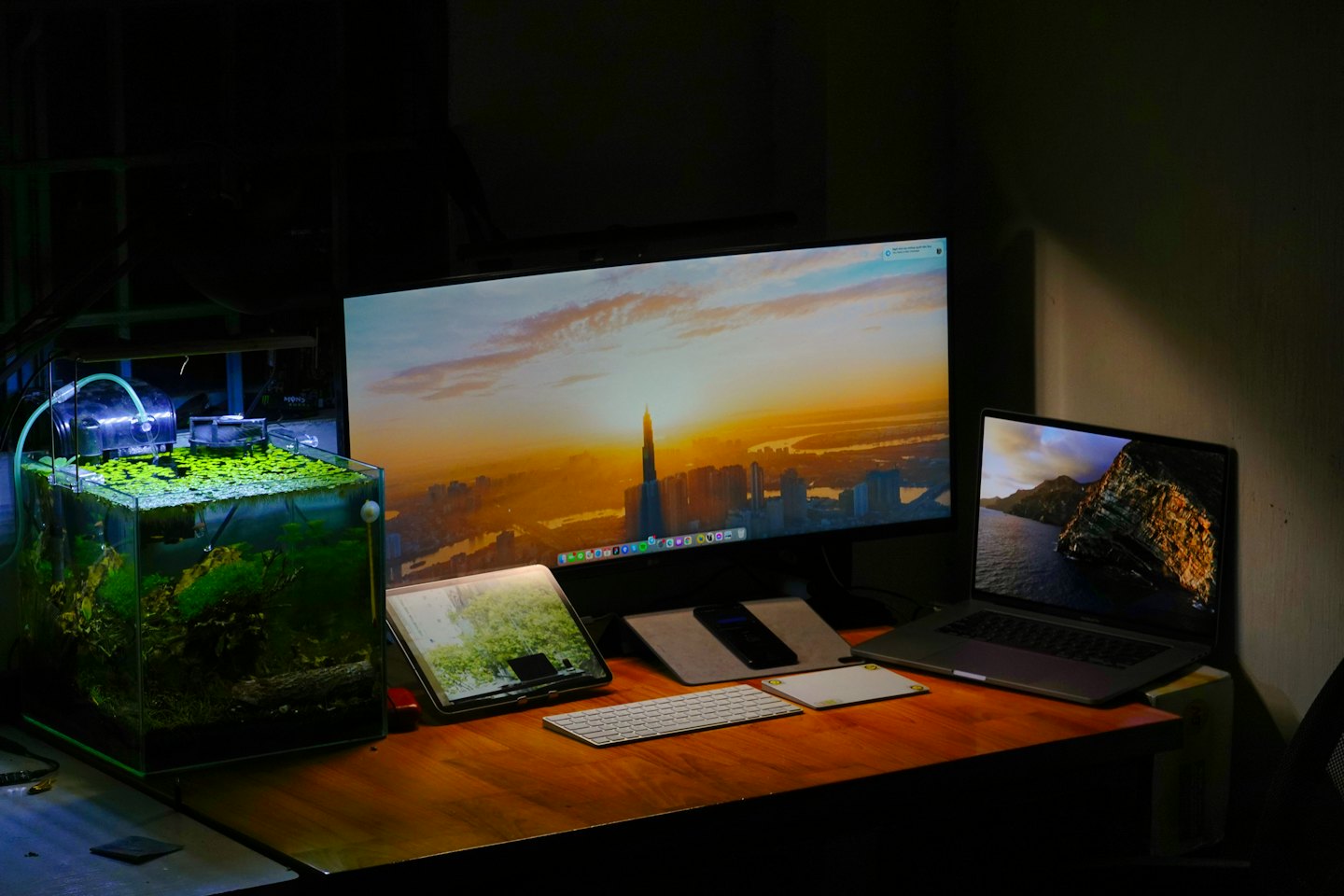 Modern computer workspace with a planted aquarium on a wooden desk.