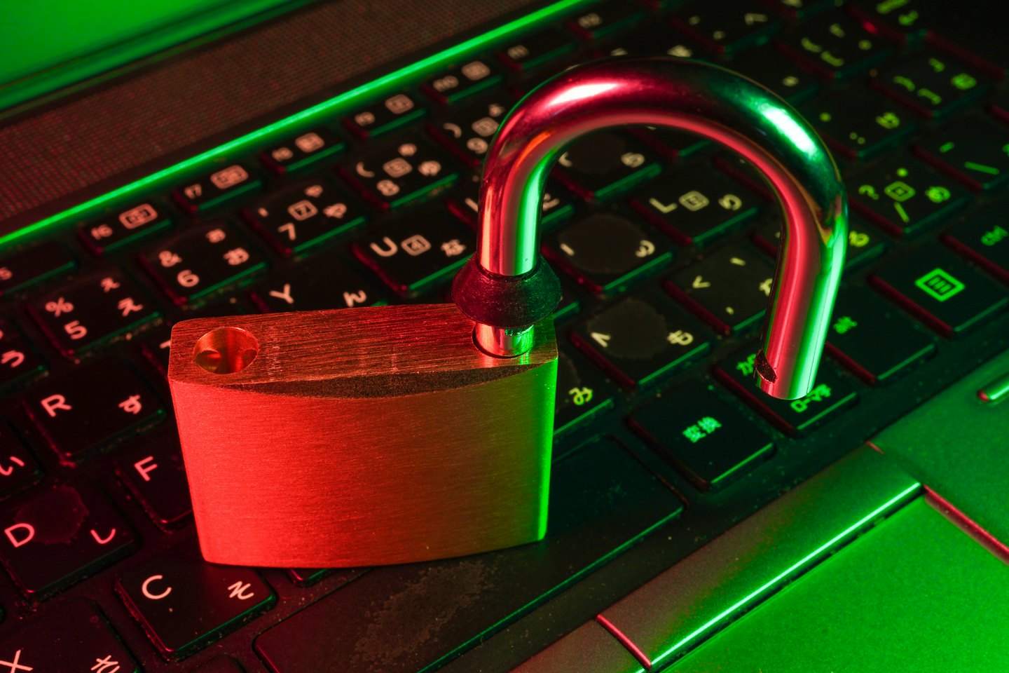 An open silver padlock sits on a laptop keyboard.